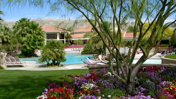 Un espace piscine comprenant des chaises longues, une piscine et un jardin aménagé avec différentes variétés de fleurs.