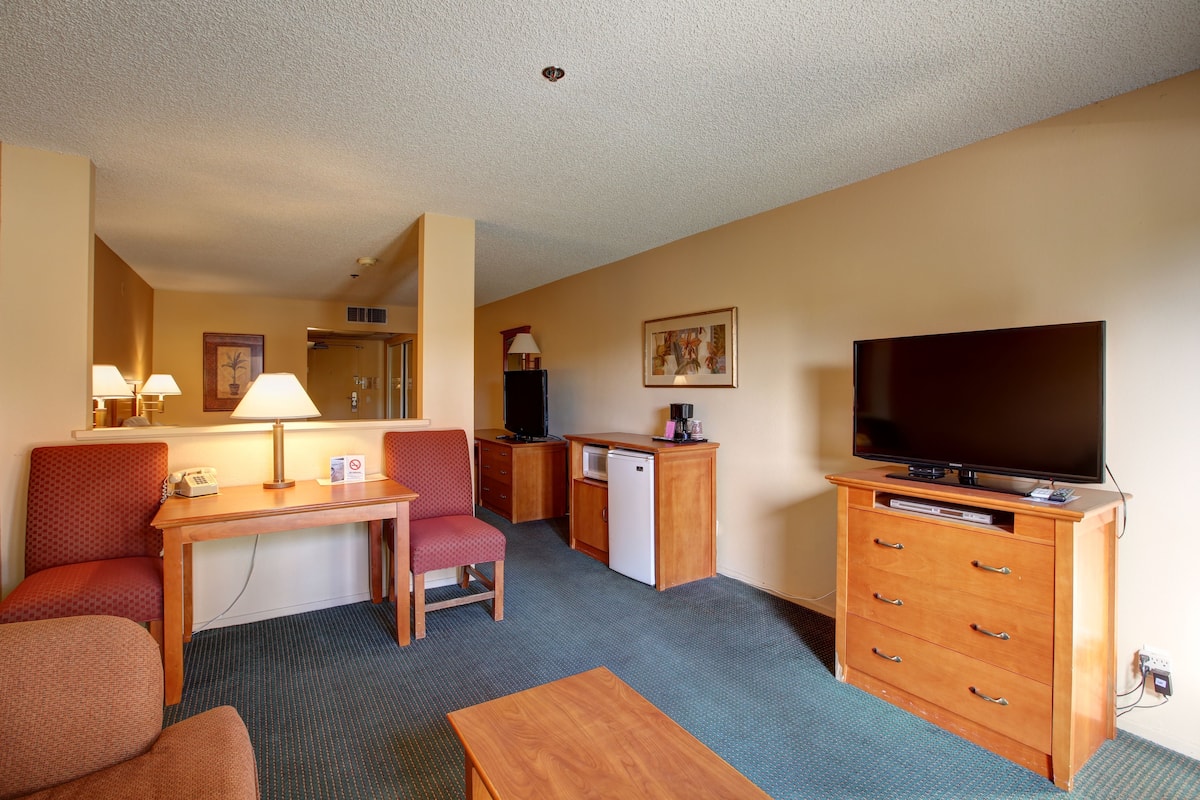 Une chambre d’hôtel équipée d’un bureau, d’une chaise, d’une télévision et d’une petite kitchenette.
