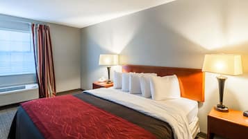 Habitación de hotel con cama, dos mesitas de noche, una lámpara en cada una, ventana con cortinas e instalación de aire acondicionado.