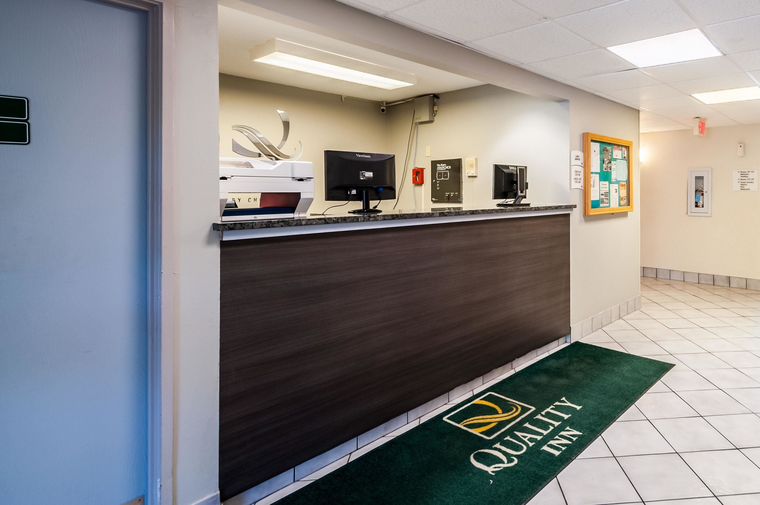 A reception desk with a computer monitor, a Xerox machine, and a bulletin board.