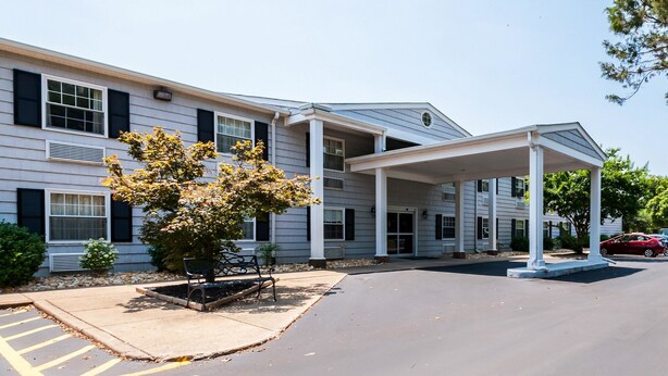 A two-story building with a covered entrance and a parking area.