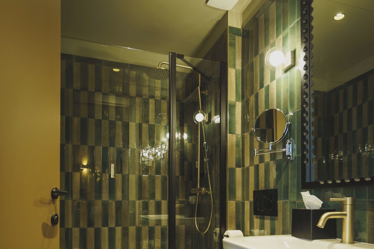 A modern bathroom with a glass-enclosed shower, a white sink, and a toilet.