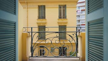 Un edificio giallo con persiane verdi e un cancello in ferro battuto nero.