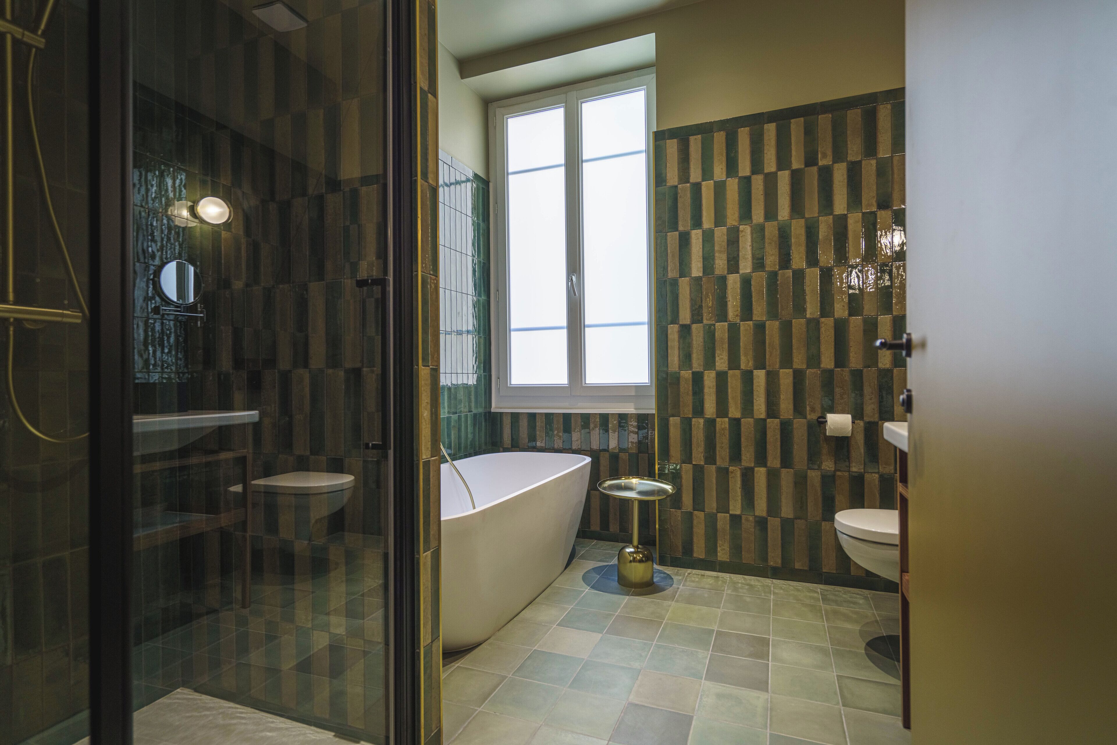 Un baño moderno con ducha de vidrio, bañera independiente y ventana que proporciona luz natural.