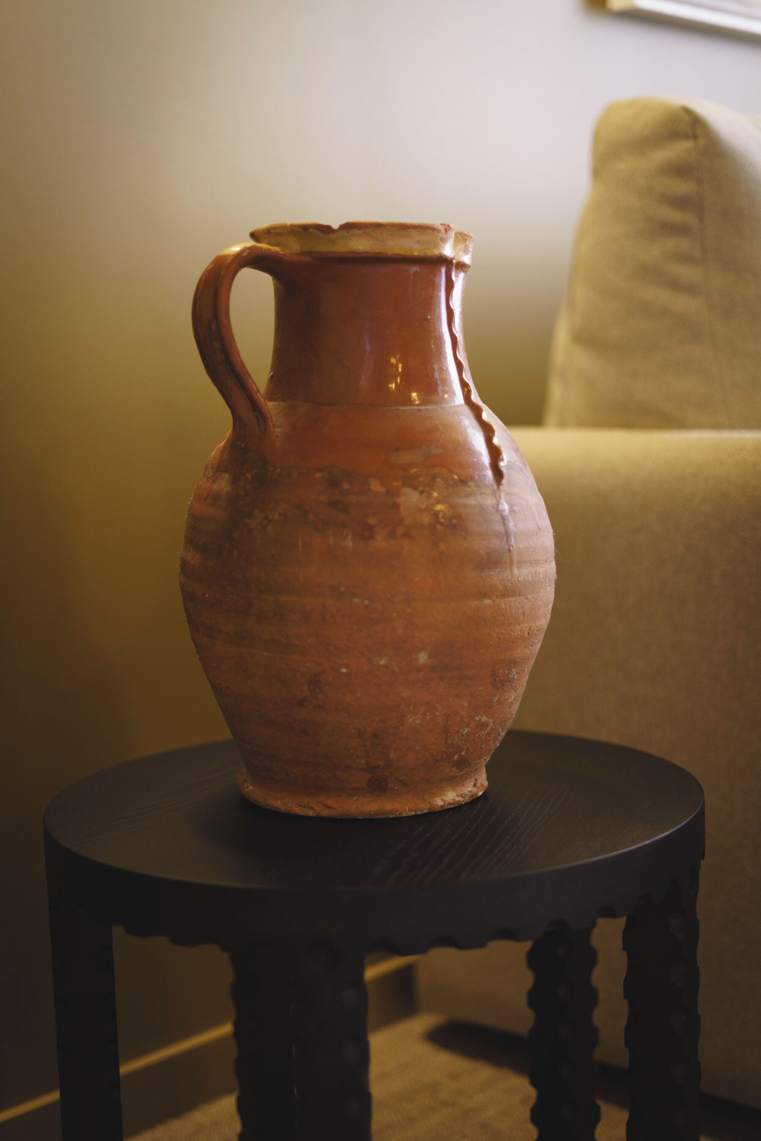 A terracotta jug on a small round table.
