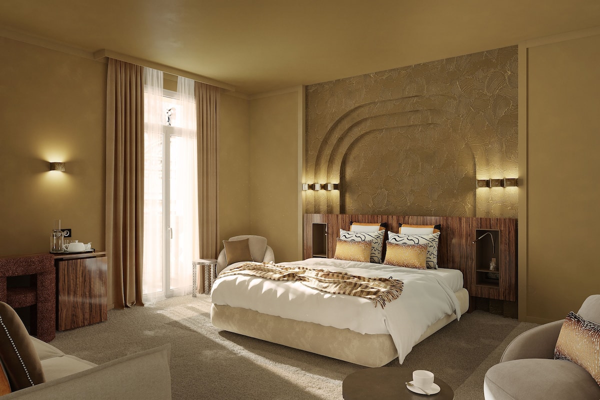 Ein Hotelzimmer mit einem großen Bett, einem Schreibtisch mit Lampe, einem Sessel und Blick ins Freie durch ein Fenster.
