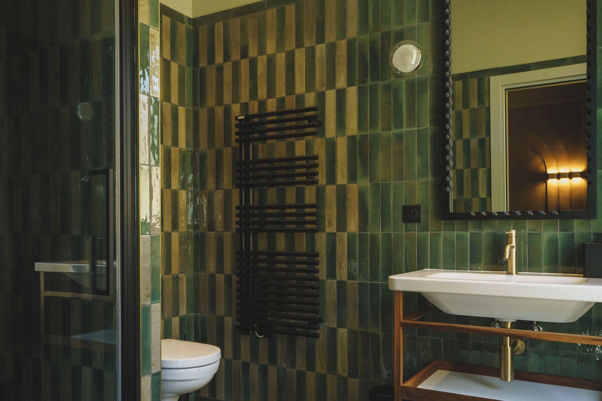 A bathroom with a glass shower enclosure, a toilet, and a sink with a mirror above it.