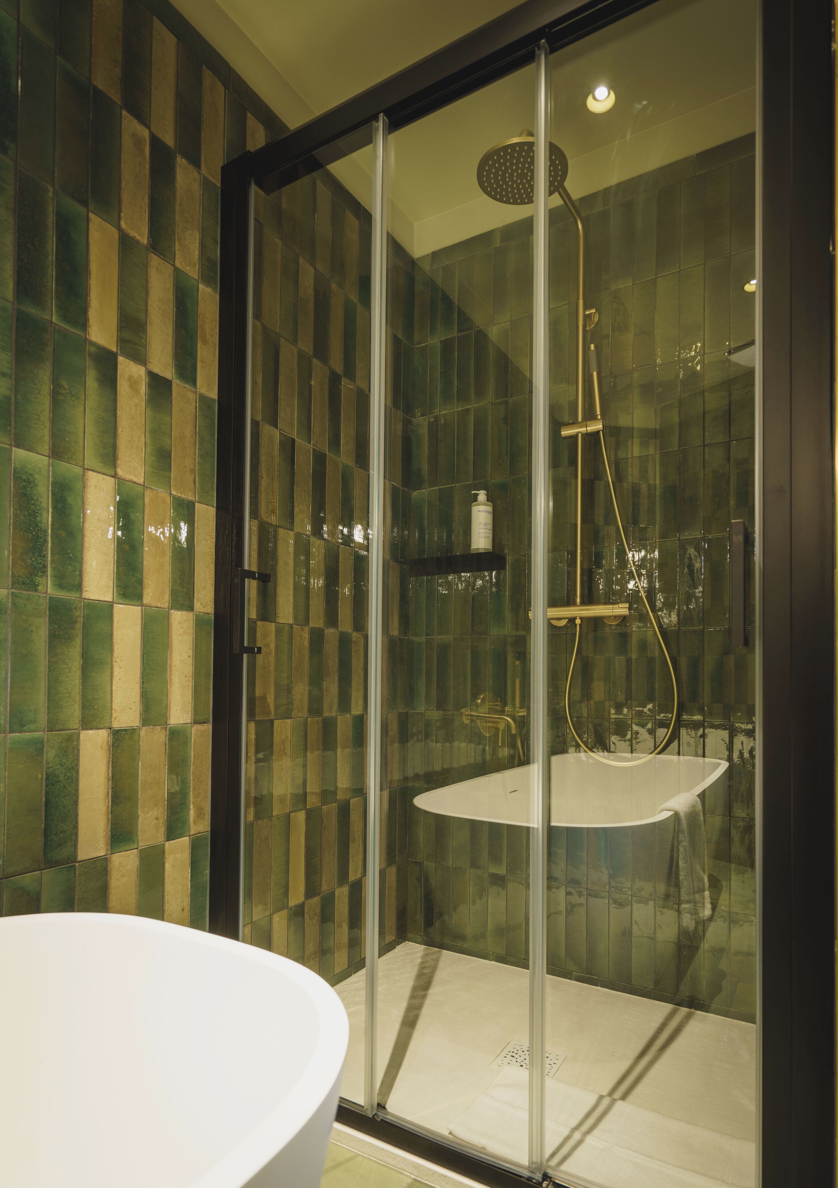 Une salle de bain moderne avec une douche à parois de verre, une baignoire blanche et des murs recouverts de carreaux à motifs géométriques.