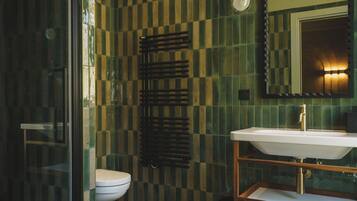 Un baño con cabina de ducha de vidrio, inodoro y lavabo con espejo.