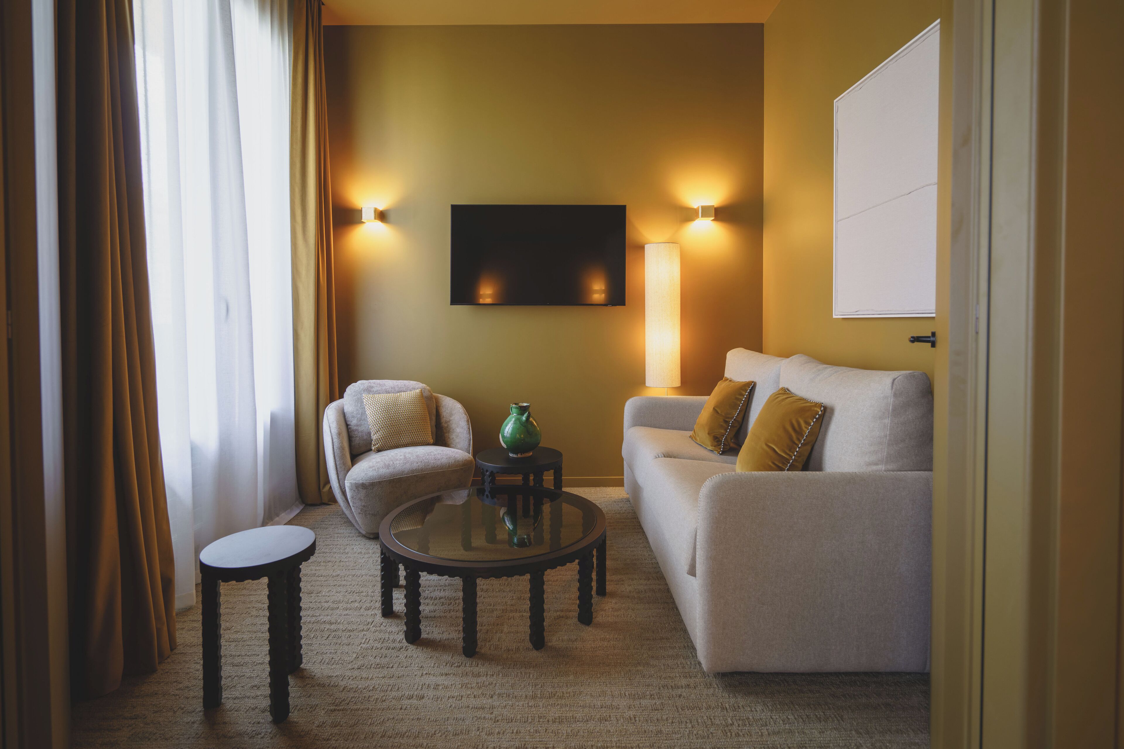 Ein Wohnzimmer mit einer Couch, einem Sessel und einem Couchtisch, ausgestattet mit einem Flachbildfernseher und Wandleuchten.