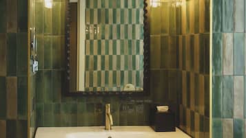 Un baño con lavamanos blanco, un espejo y un perchero para toallas.