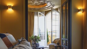 Habitación de hotel con una cama grande, una mesita con una planta y vistas al exterior a través de un ventanal.