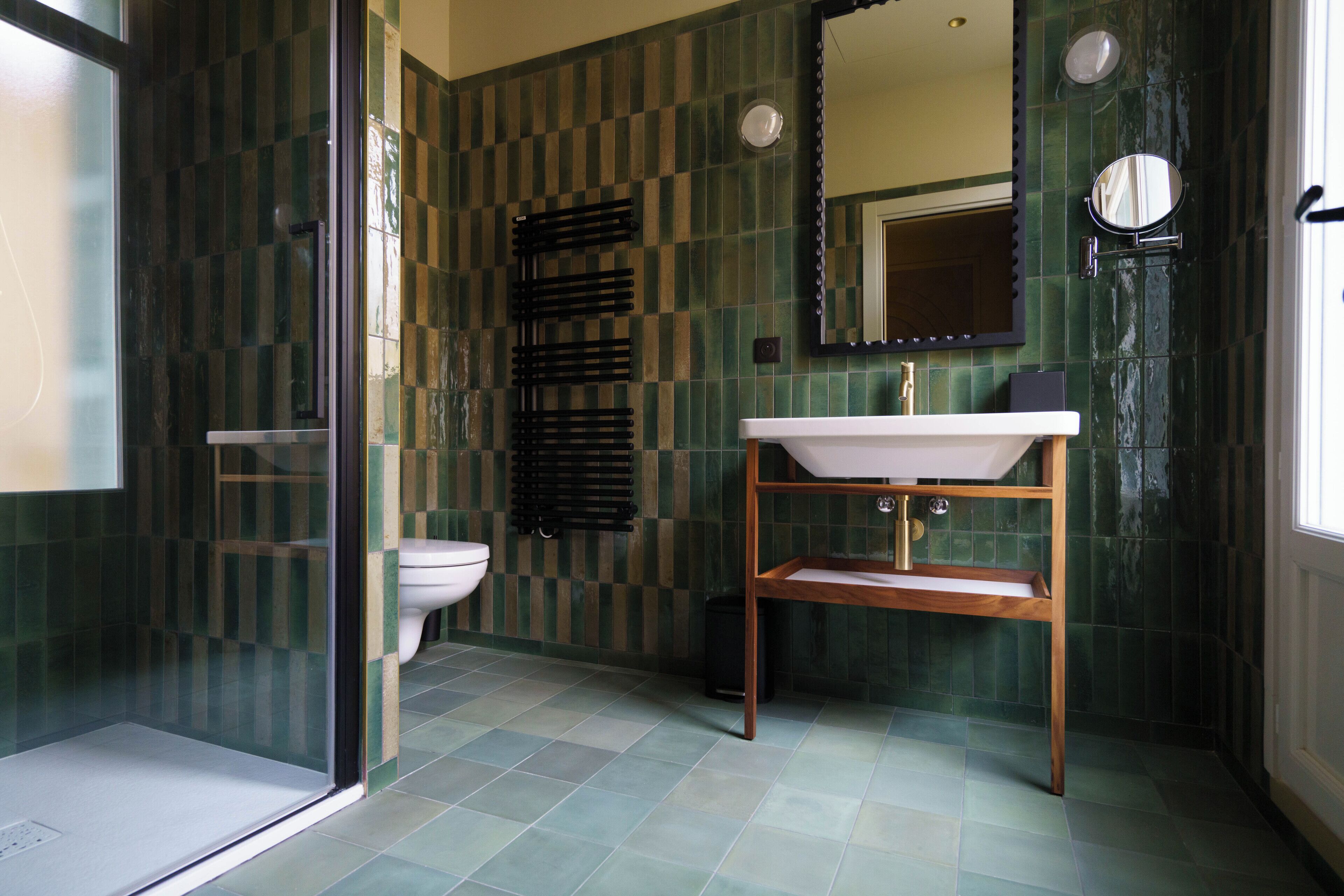 A bathroom with a checkered tile wall, a white sink, a mirror, and a glass shower enclosure.