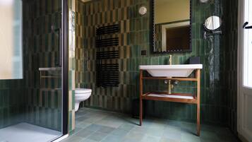 A bathroom with a checkered tile wall, a white sink, a mirror, and a glass shower enclosure.