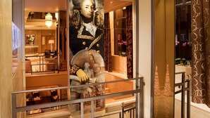 A hotel lobby with a large portrait, a reception desk, and a staircase. - Best Western Anjou Lafayette Opera (Paris)