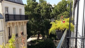 A balcony with a view of a park, a building with a balcony, and a tree. - Best Western Anjou Lafayette Opera (Paris)