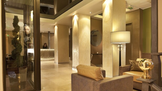 A modern lobby with a reception desk, seating area, and a decorative lamp. - Best Western Anjou Lafayette Opera (Paris)
