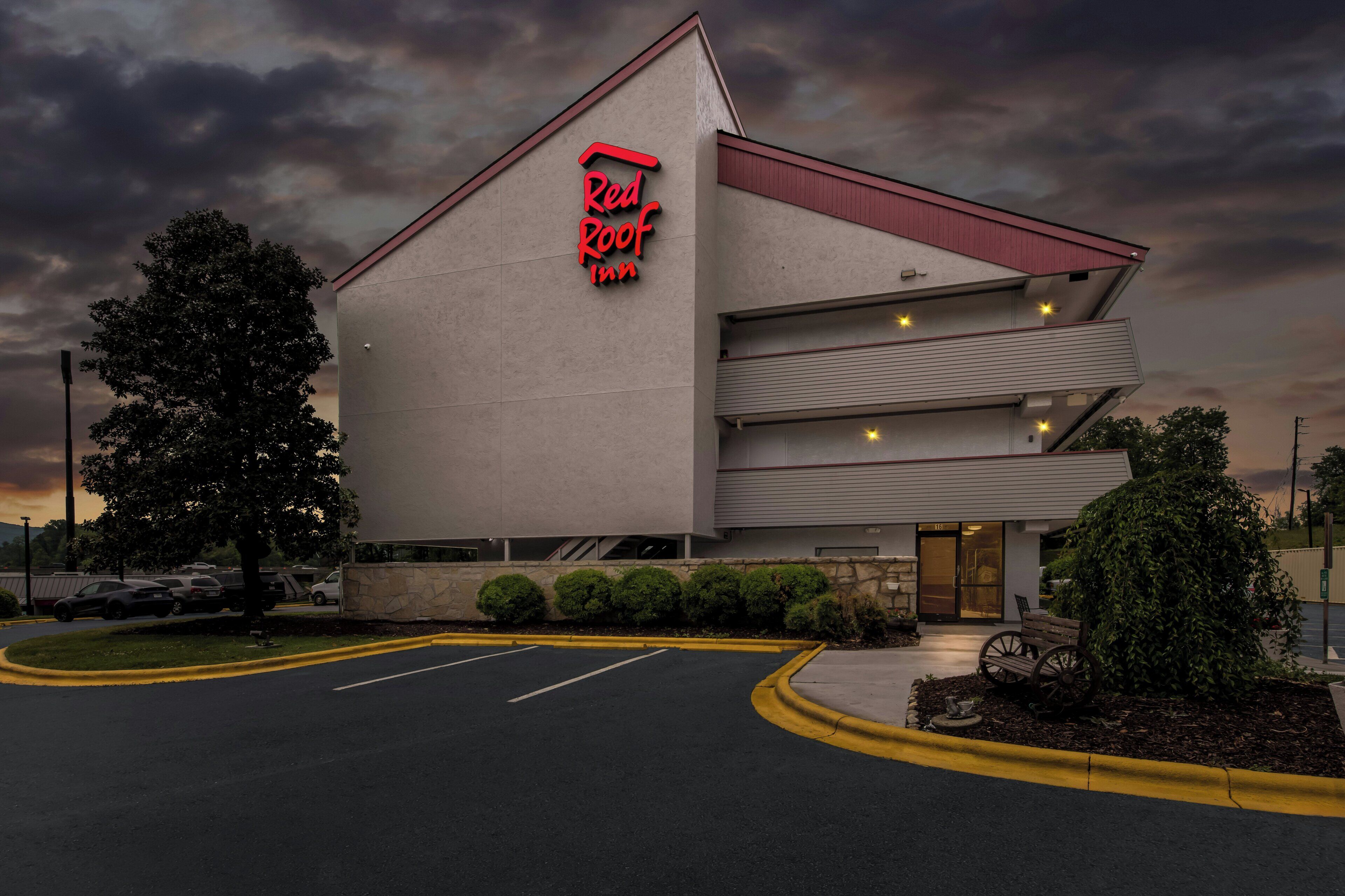 A Red Roof Inn with a modern design, featuring a prominent red logo, a parking lot, and a well-maintained exterior.