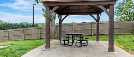 A gazebo with a roof and four picnic tables.