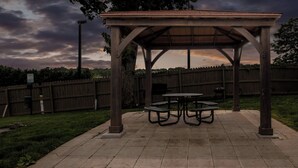 A gazebo with a table and benches, surrounded by a wooden fence and a grassy area. - Red Roof Inn Asheville - Biltmore West (Asheville)