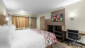 A hotel room with a bed, a desk, a television, and a minibar.