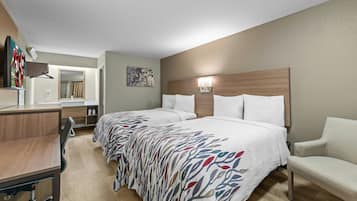A hotel room with two beds, a desk, a chair, a TV, and a bathroom.