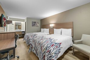 Habitación de hotel con dos camas, un escritorio, una silla, un televisor y un baño.