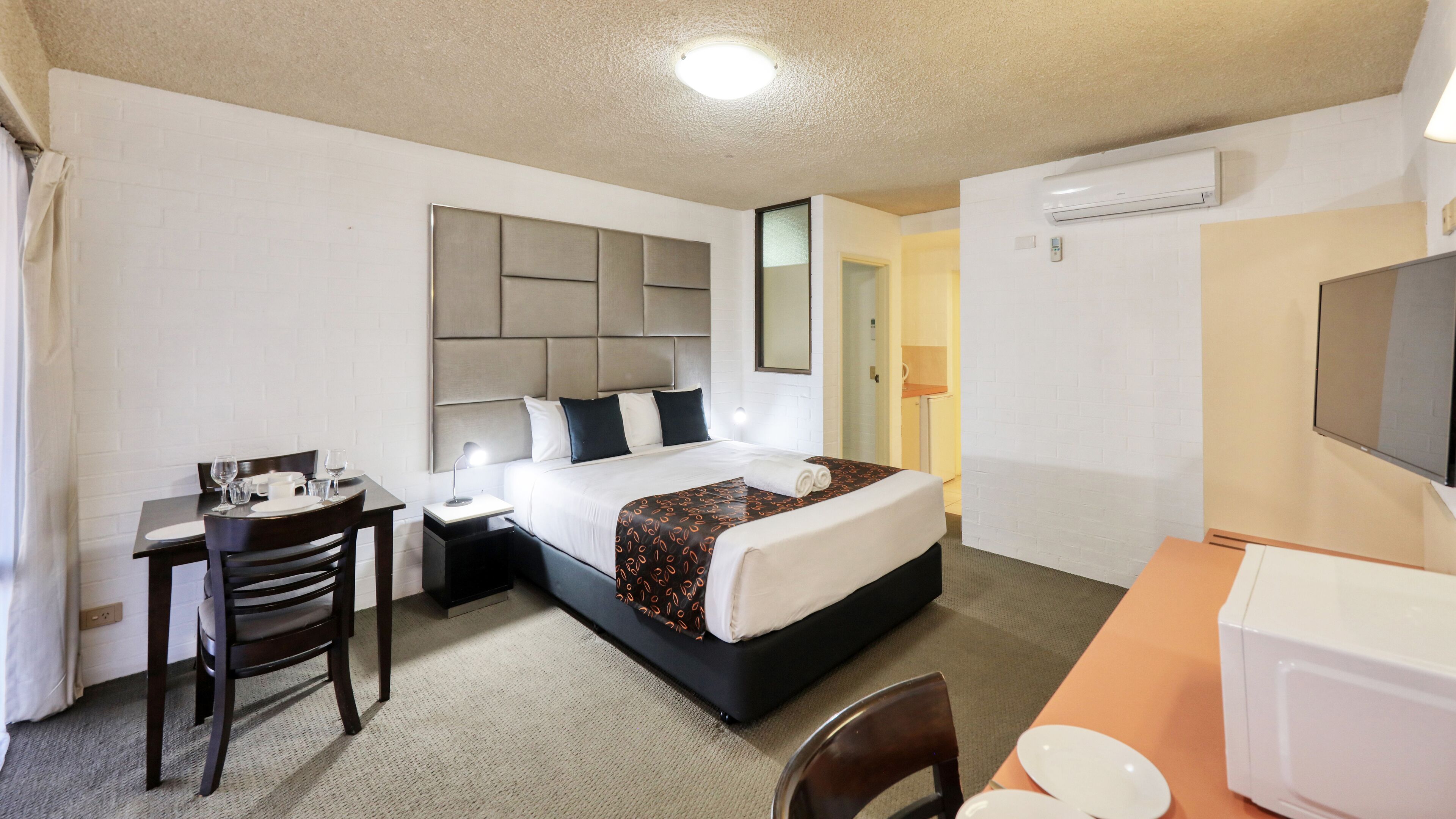 Een hotelkamer met een bed, een bureau, een stoel, een televisie en een magnetron.