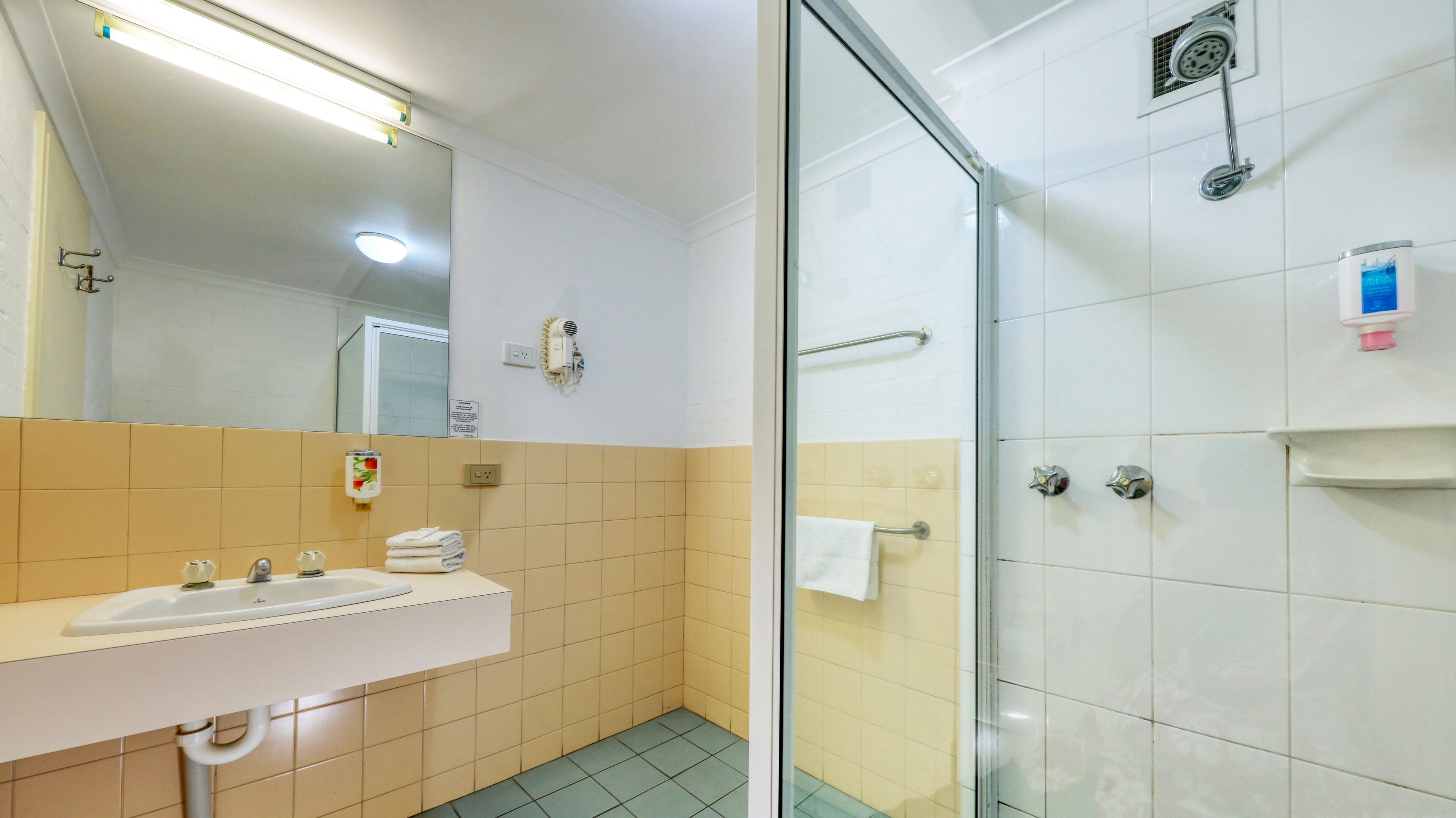 A bathroom with a sink, mirror, towel rack, and a glass shower enclosure.