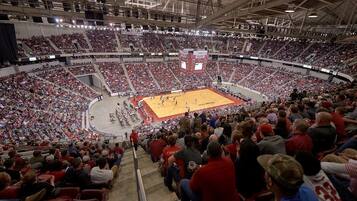 A large indoor sports arena with multiple levels of seating, a central ice rink, and a scoreboard.