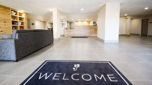 A spacious lobby with a reception desk, a sofa, and a welcome mat.