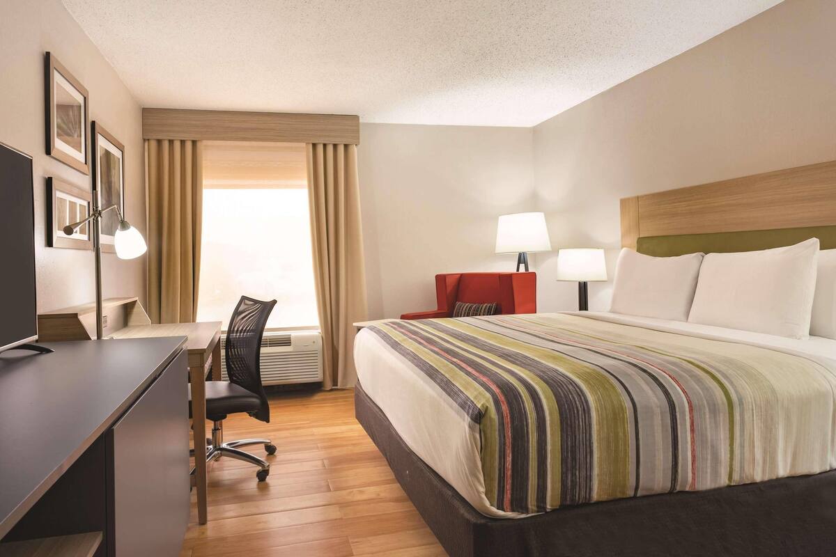 A hotel room with a bed, desk, chair, and two lamps.