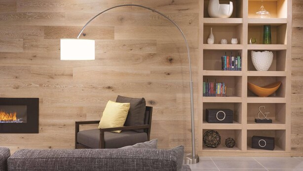 A modern living room with a fireplace, a bookshelf, and a curved floor lamp.