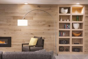 A modern living room with a fireplace, a bookshelf, and a curved floor lamp. - Country Inn & Suites by Radisson, North Little Rock, AR (North Little Rock)