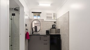 A compact kitchen with a microwave, coffee maker, and a small refrigerator. - Alabaster Motor Inn Taree (Taree)