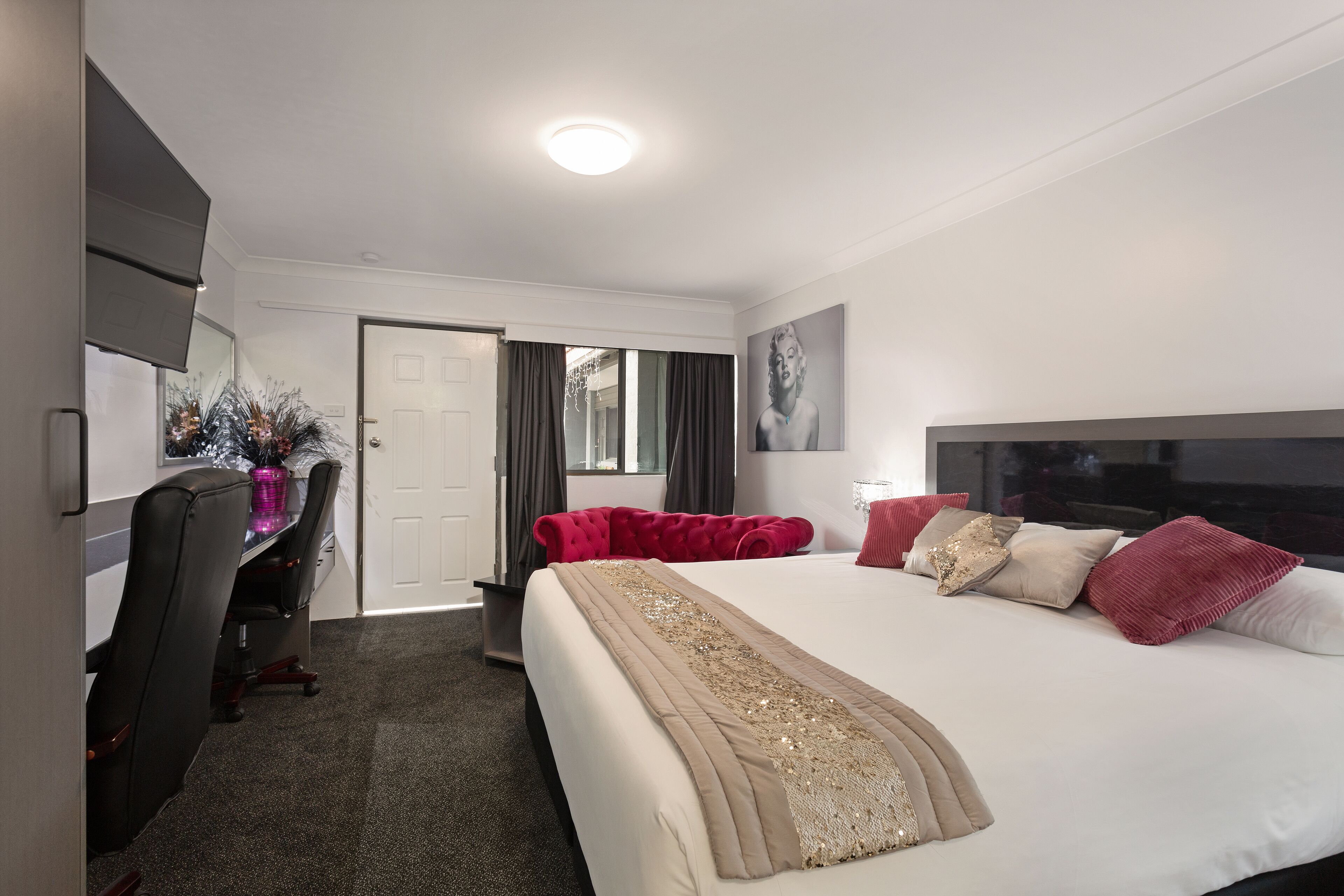 Une chambre d’hôtel avec un grand lit, un bureau avec une chaise, une télévision et une porte.