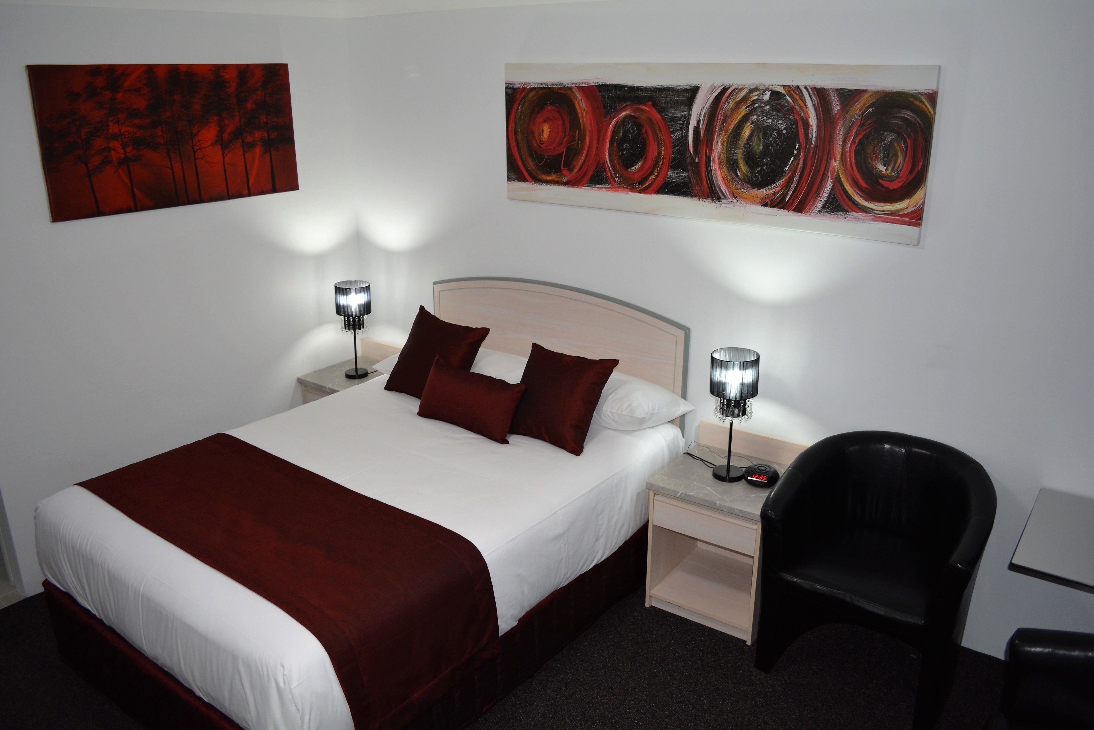 A hotel room with a large bed, two bedside tables with lamps, a desk, and a chair.