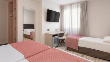 A hotel room with two beds, a desk, a chair, a TV, and a wardrobe.