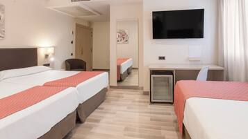 A hotel room with two beds, a desk, a television, and a small refrigerator.