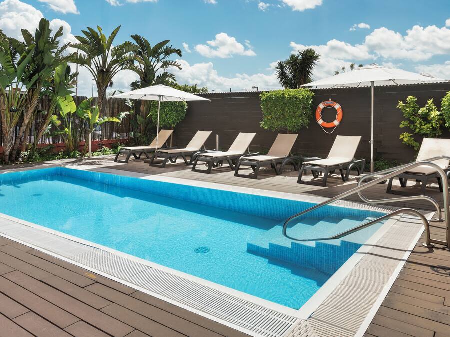 Una piscina al aire libre, sillones reclinables de piscina