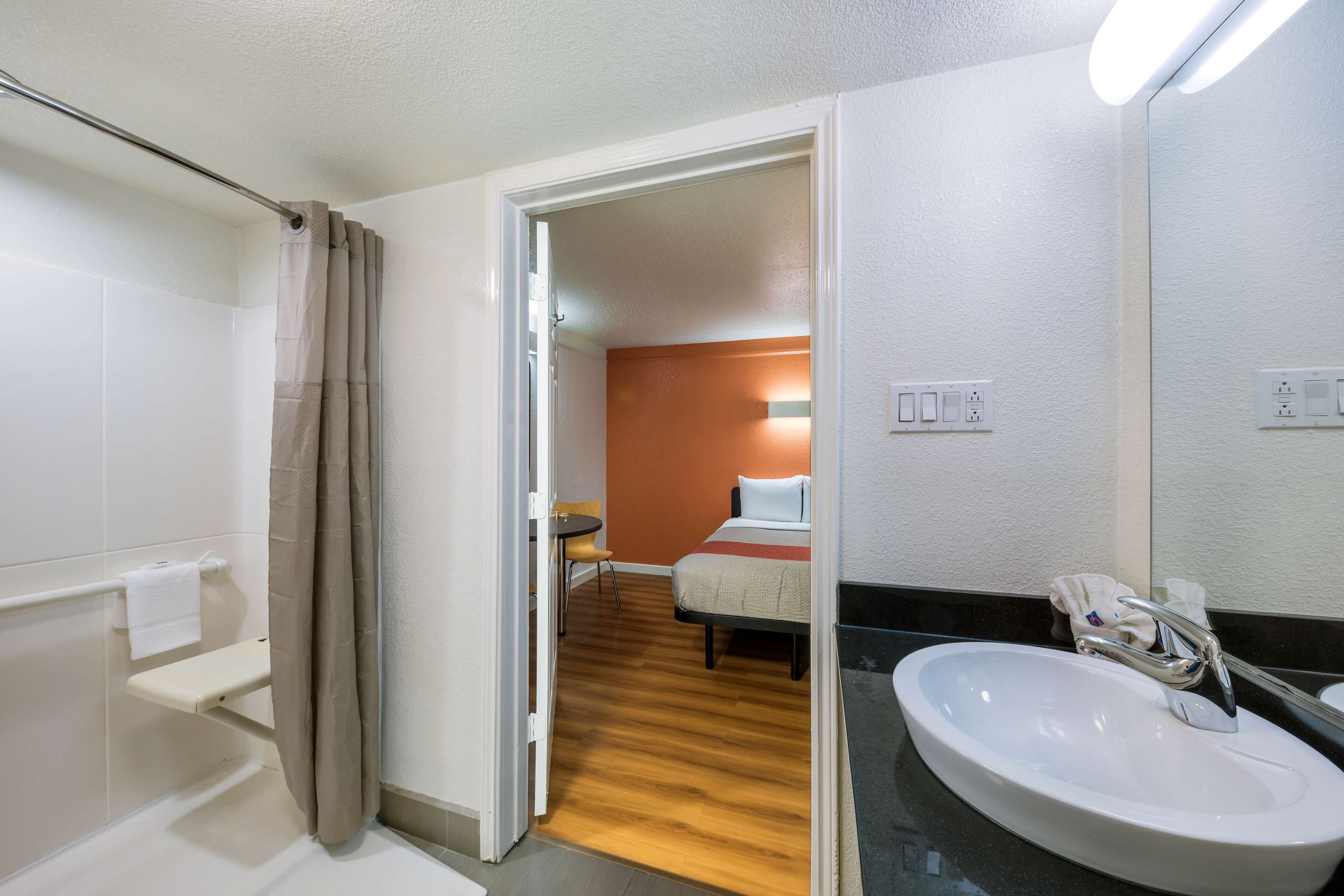 A hotel bathroom with a sink, mirror, and shower.