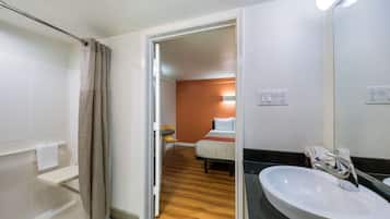 A hotel bathroom with a sink, mirror, and shower.