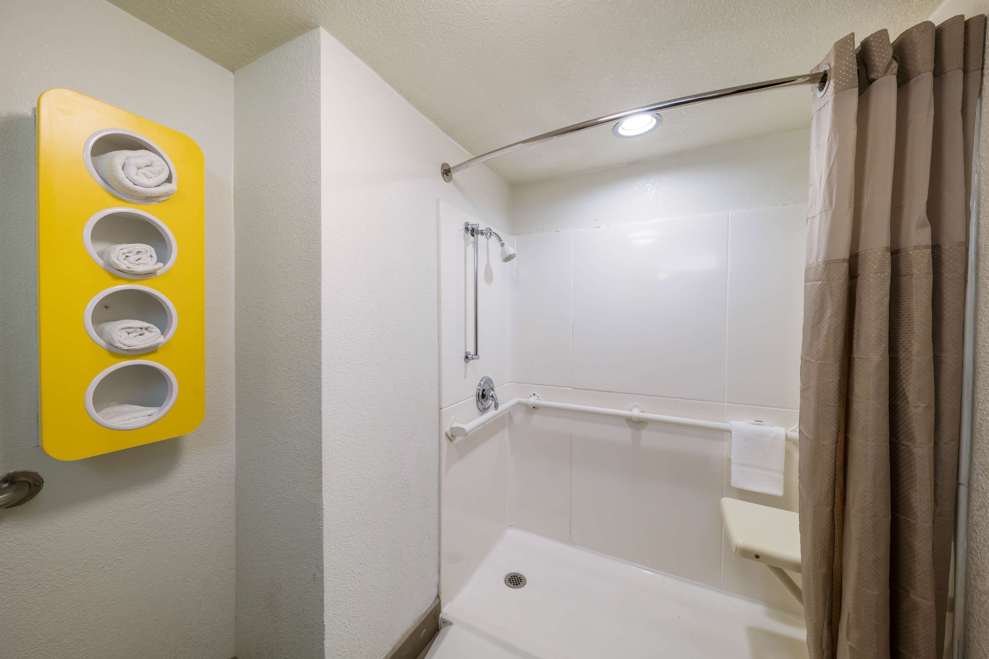 Een badkamer met een douche, toilet en wastafel. Drie handdoekdispensers zijn aan de muur bevestigd.