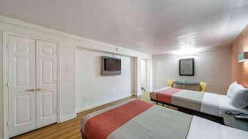 A hotel room with two beds, a TV, a small table, and a desk with a chair.