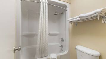 A bathroom with a bathtub, shower, toilet, and towel rack.