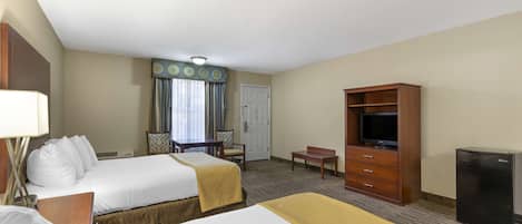 Ein Hotelzimmer mit zwei Betten, einem Schreibtisch, einem Fernseher, einem Kühlschrank und einem Kleiderschrank.