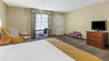 Una habitación de hotel con cama, escritorio, silla, televisor y cómoda.