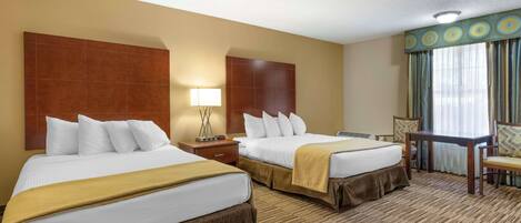A hotel room with two beds, a desk, a chair, and a window with curtains.