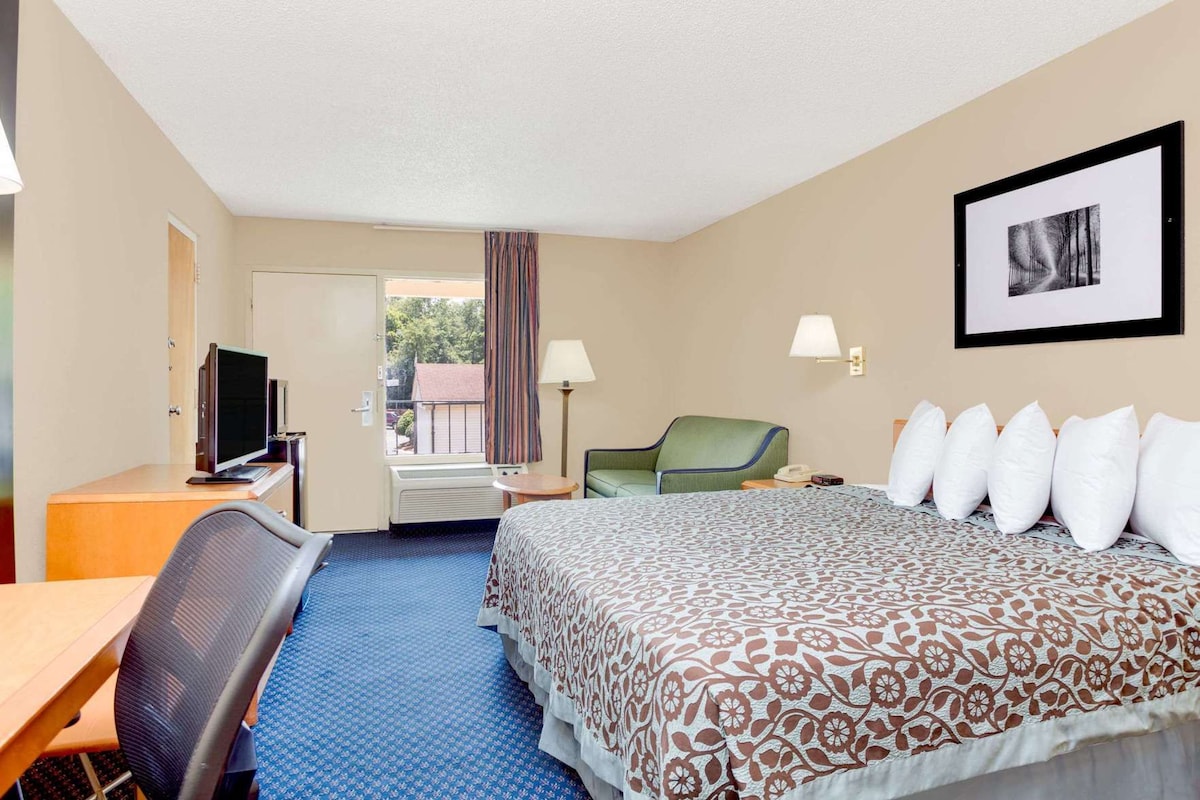 A hotel room with a bed, desk, chair, and a window with curtains.
