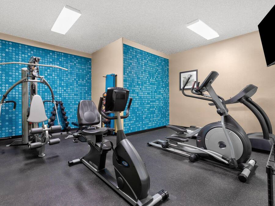 A gym with exercise equipment, including a stationary bike, elliptical, and weight machine.